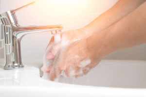 person soaping their hands under a tap